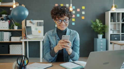 Женщина использует смартфон за рабочим столом