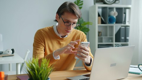 Мужчина использует смартфон за рабочим столом